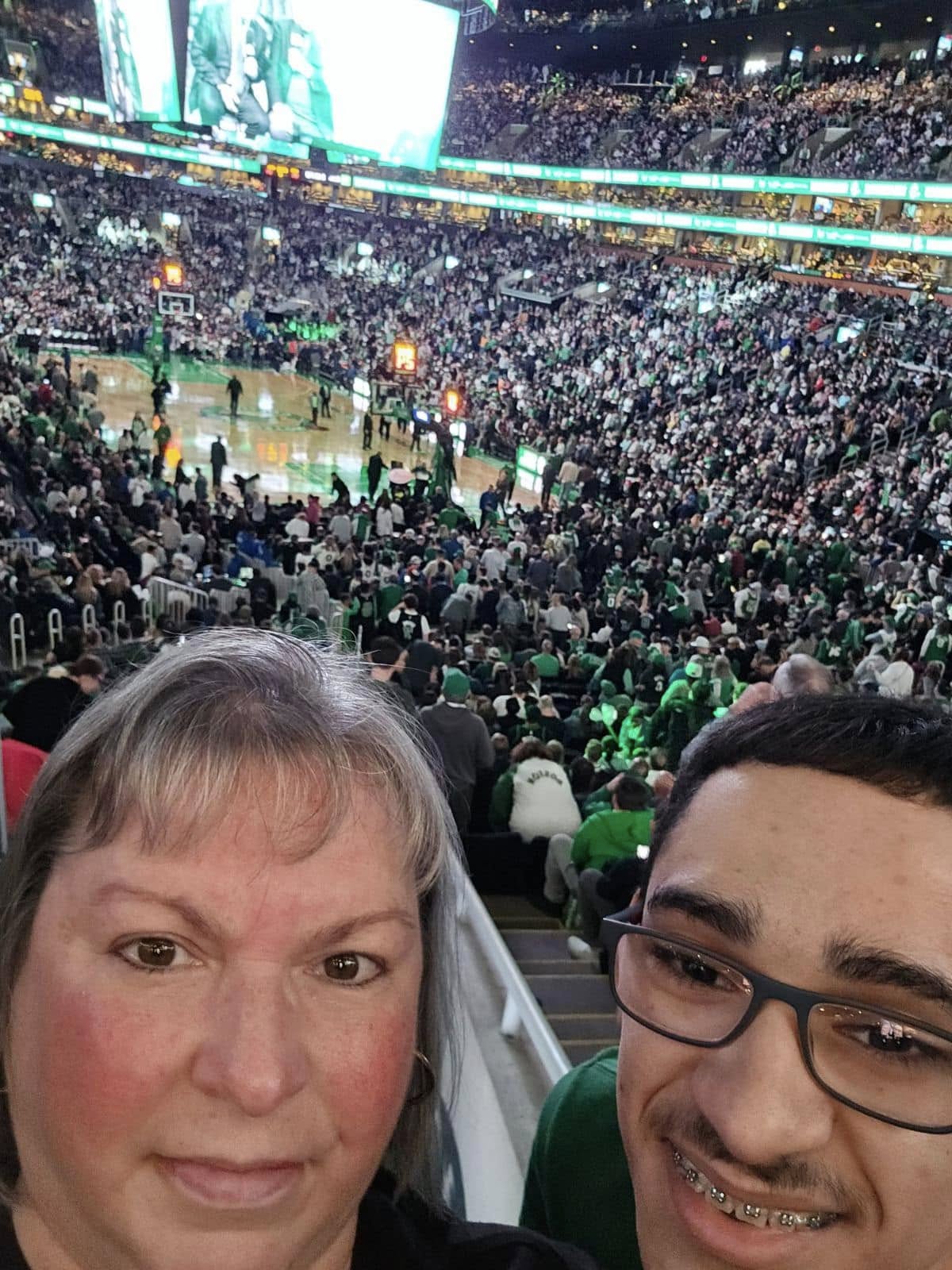 Two people taking a selfie in the stands at a Boston Celtics basketball game