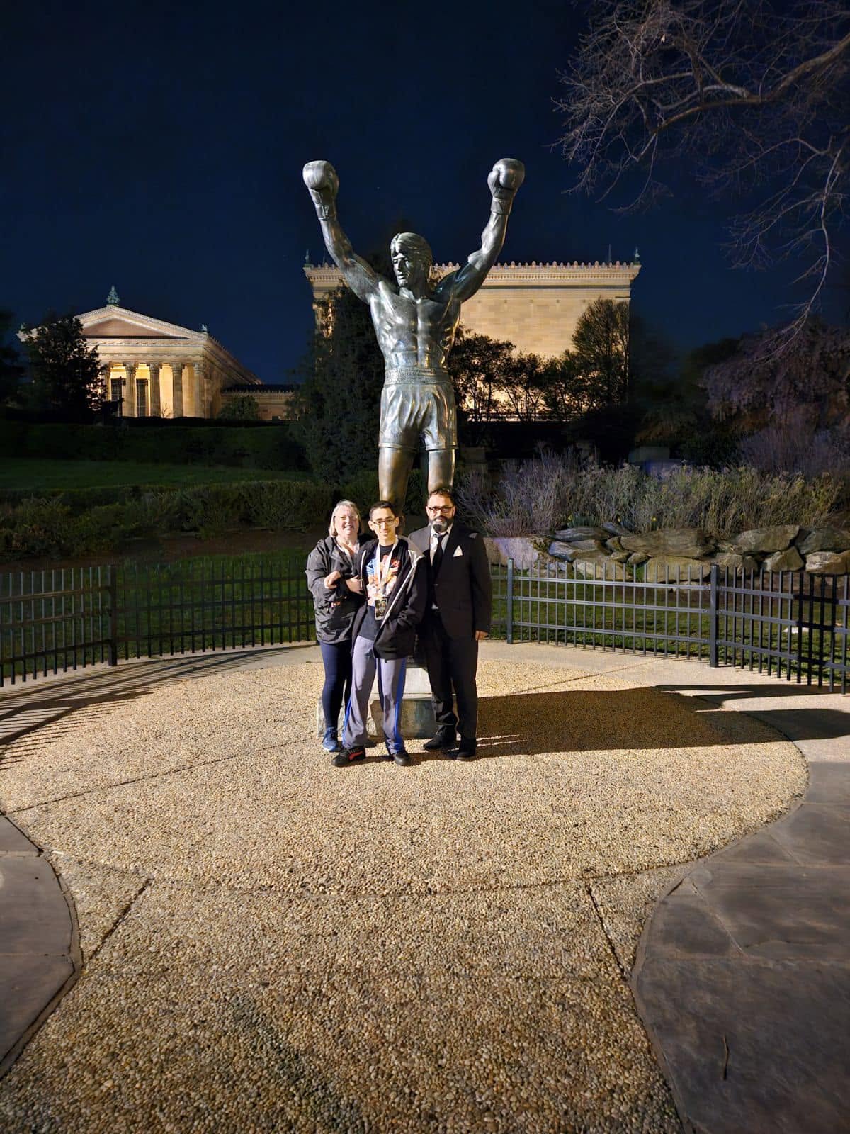Family posing together in front of the Rocky statue in Philadelphia at night